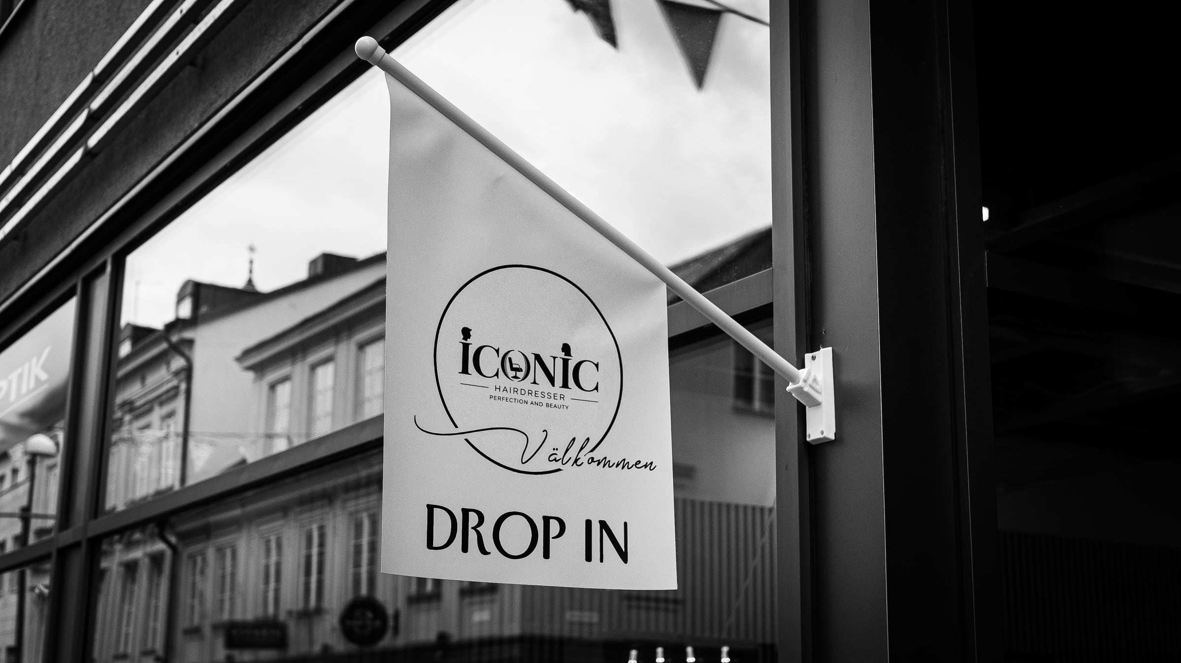 Flagga med texten Välkommen, drop in utanför Salong Iconic